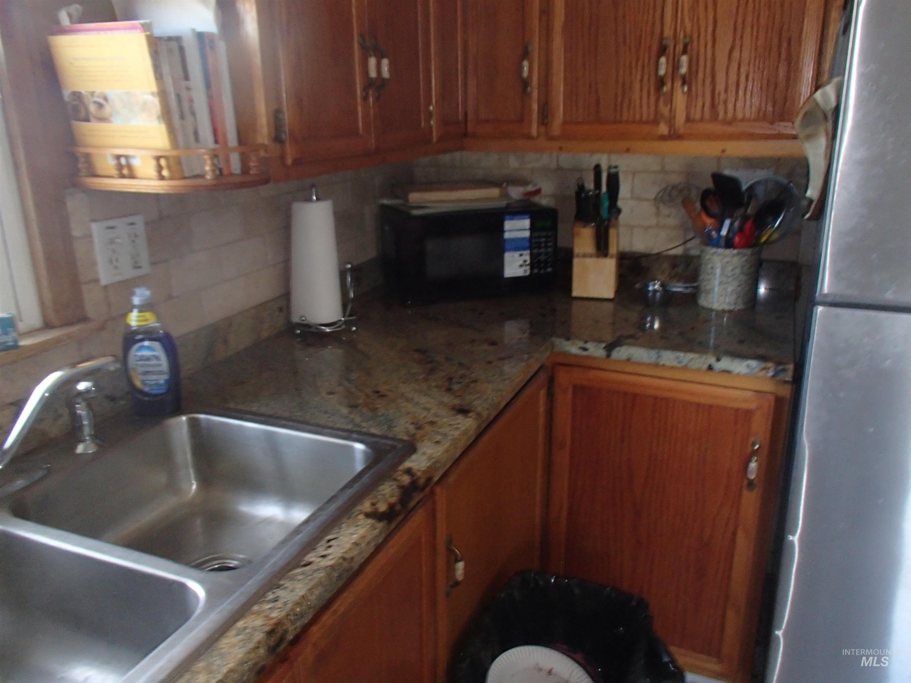 9506 Wright Road Melba, ID 83641 - Photo 6 of 37 Kitchen featuring wood finish cabinetry, freestanding refrigerator, backsplash, and black microwave