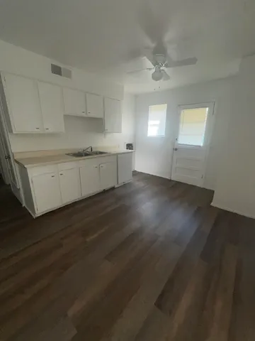 a kitchen with granite countertop a stove a sink and white cabinets with wooden floor