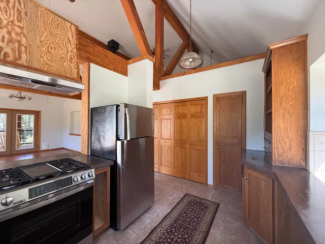 a view of a kitchen with stainless steel appliances granite countertop a refrigerator and a stove top oven