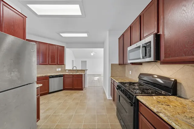 a kitchen with stainless steel appliances granite countertop a stove refrigerator sink and microwave