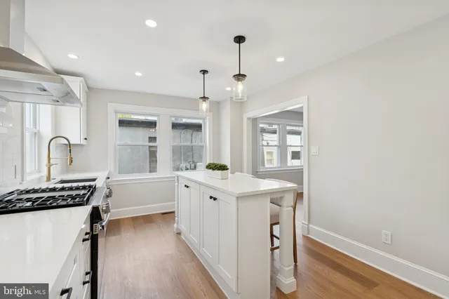 a kitchen that has a sink a stove and a table with wooden floor