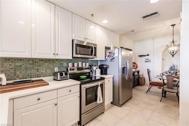 a kitchen with refrigerator a microwave a stove and white cabinets