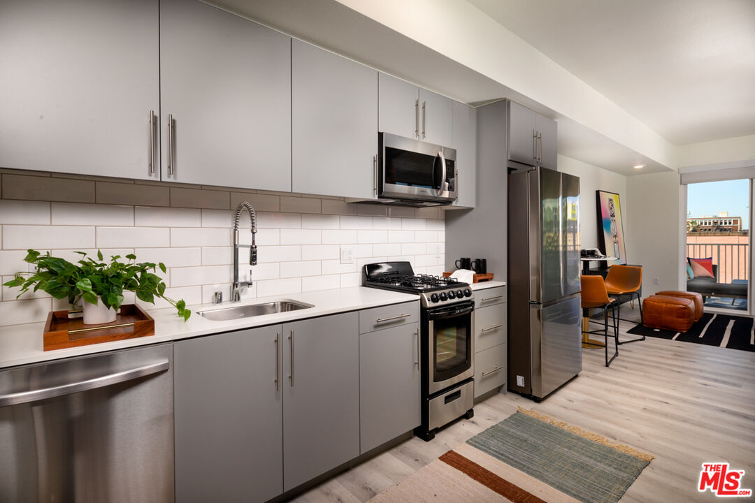 750 South Oxford Avenue, Unit 430 Los Angeles, CA 90005 - Photo 26 of 28 a kitchen with stainless steel appliances a sink a stove top oven a chimney cabinets and dining table