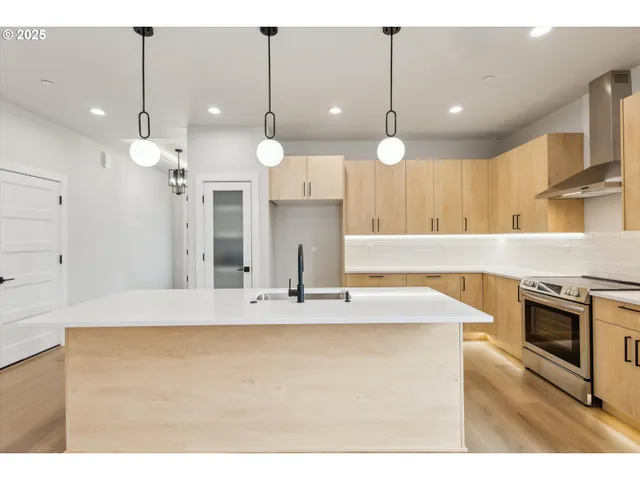 a large kitchen with kitchen island a stove a sink a center island and a wooden floor