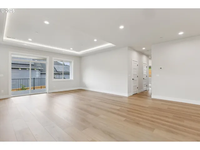 a view of an empty room with wooden floor and windows