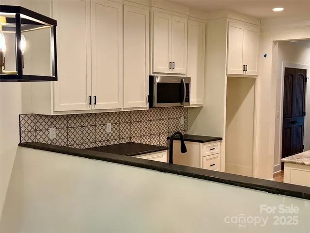 a view of kitchen with stainless steel appliances granite countertop white cabinets and a refrigerator