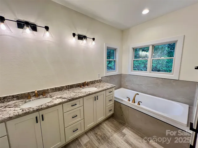a bathroom with a granite countertop tub a sink and a window