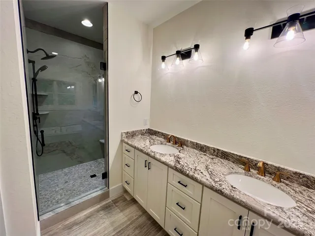 a bathroom with a granite countertop sink a mirror and shower