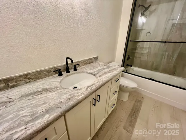 a bathroom with a granite countertop sink a toilet and a mirror