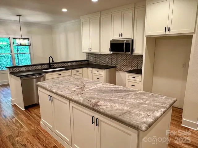 a kitchen with stainless steel appliances granite countertop a sink stove and microwave