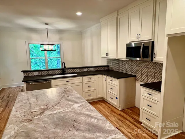 a kitchen with granite countertop white cabinets and black appliances