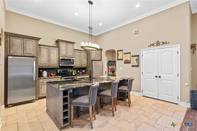 a kitchen with stainless steel appliances a table chairs refrigerator and microwave