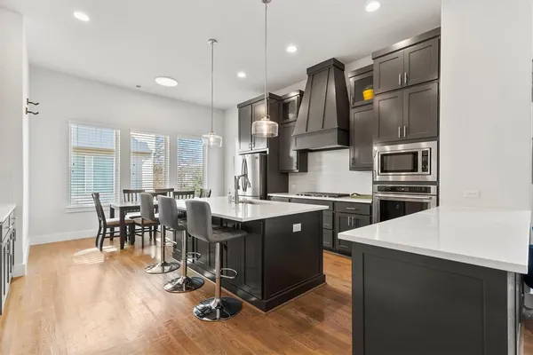 a kitchen with stainless steel appliances granite countertop a table chairs and a refrigerator