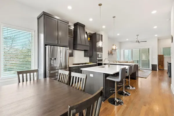 an open kitchen with kitchen island wooden floor center island and stainless steel appliances
