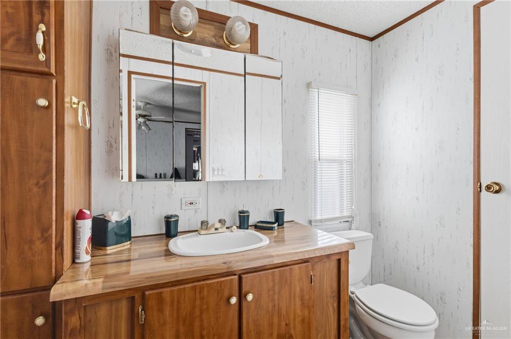 215 South Valley View Road, Unit 15&16 Donna, TX 78537 - Photo 10 of 13 a bathroom with a granite countertop sink toilet and mirror
