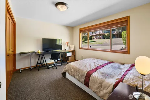 a bedroom with a bed a computer on the desk and a large window