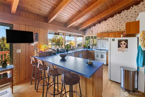 a kitchen with stainless steel appliances granite countertop a stove a refrigerator a sink a dining table and chairs with wooden floor