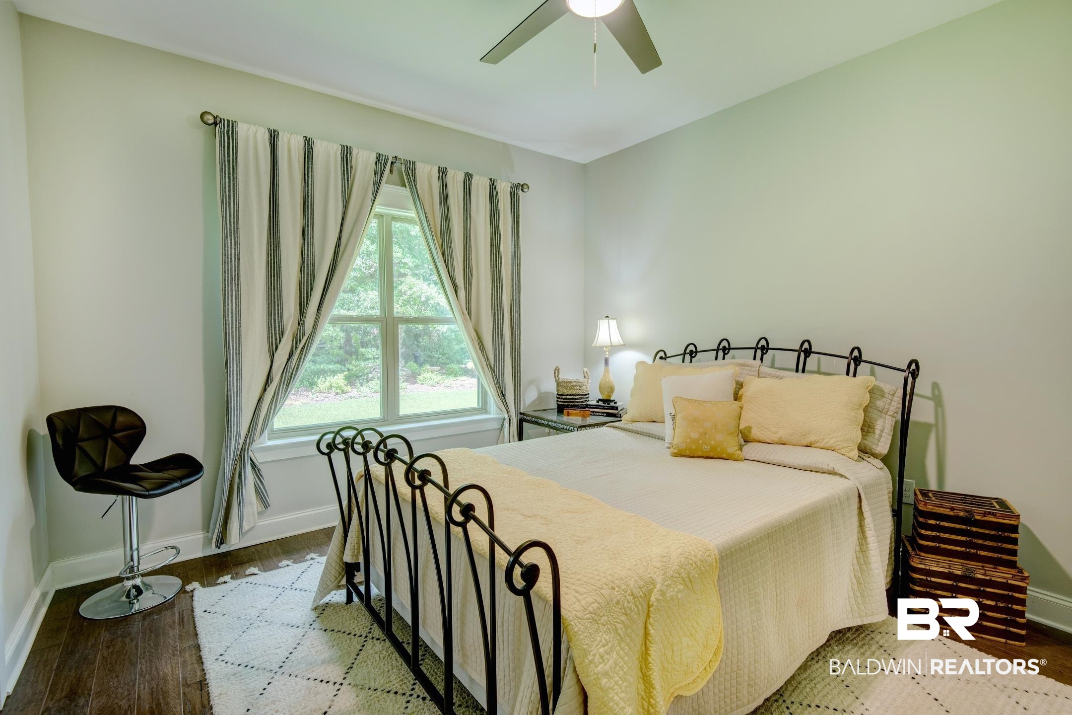 18754 Treasure Oaks Road Gulf Shores, AL 36542 - Photo 39 of 53 Hardwood-finish flooring featuring a window with exterior tree scenery, a ceiling fan, and painted walls
