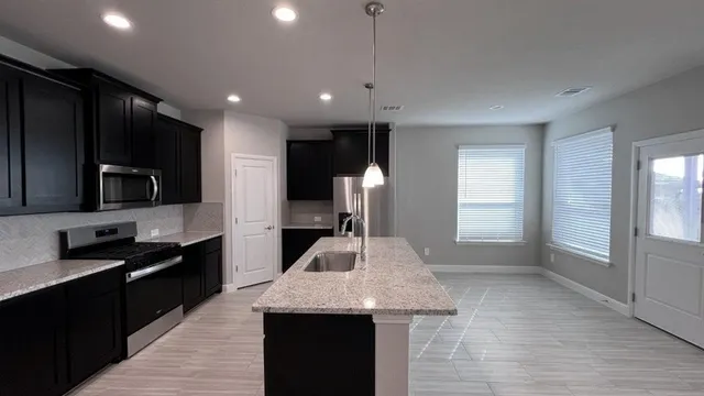 a large kitchen with stainless steel appliances kitchen island a large counter top and a refrigerator