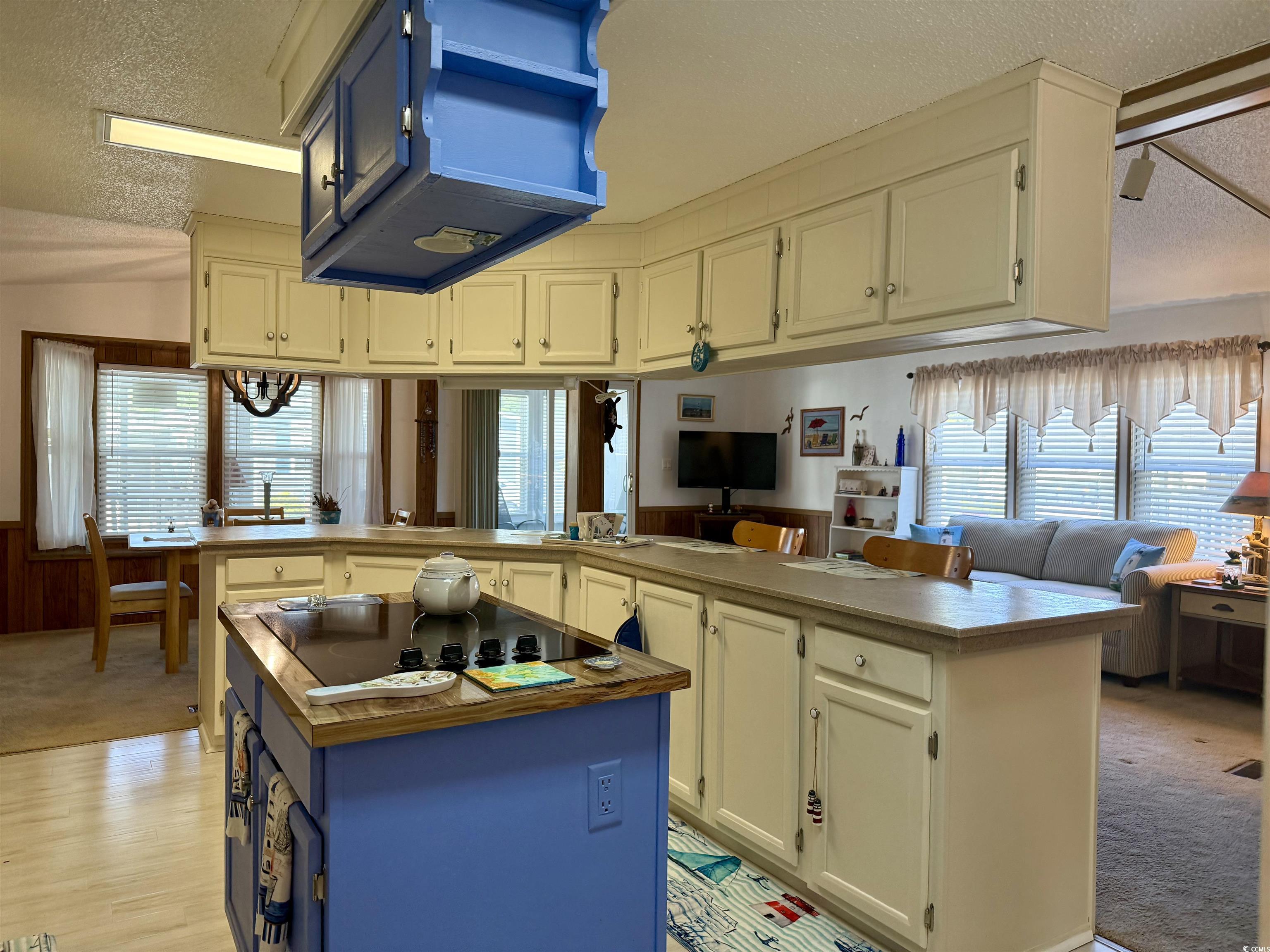 505 Sandpebble Surfside Beach, SC 29575 - Photo 2 of 27 Kitchen with black electric cooktop, a center island, a textured ceiling, a wainscoted wall, and blue cabinets