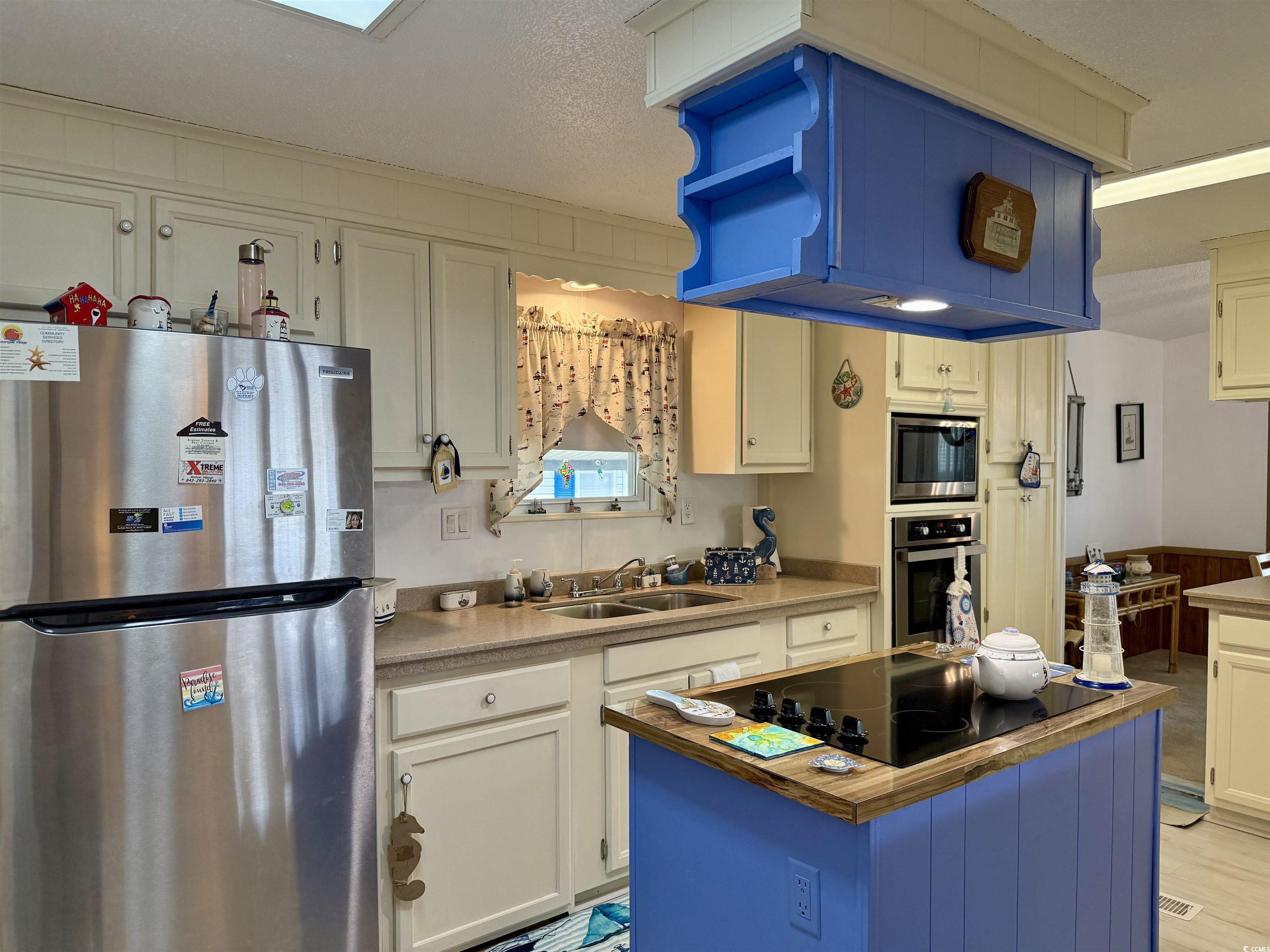 505 Sandpebble Surfside Beach, SC 29575 - Photo 3 of 27 Kitchen with stainless steel appliances, a sink, white cabinetry, and a center island