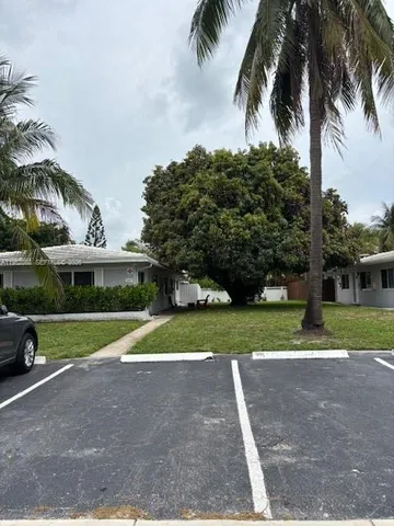 a view of a house with a yard and palm trees
