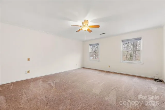 an empty room with windows and fan