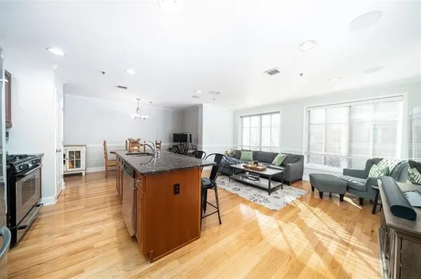 a living room with stainless steel appliances furniture a rug and a kitchen view