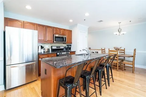 a kitchen with granite countertop a table chairs microwave and refrigerator
