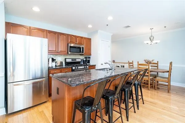 a kitchen with granite countertop a table chairs microwave and refrigerator