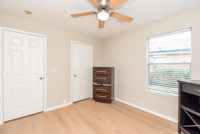 an empty room with a window and a fan