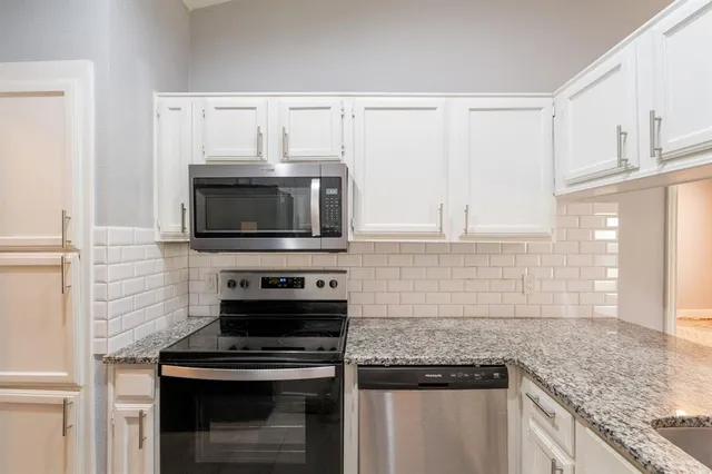 a kitchen with granite countertop a stove sink and microwave