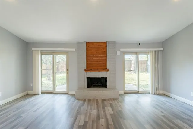 an empty room with wooden floor fireplace and windows