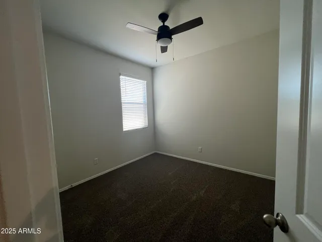 an empty room with a window and a ceiling fan