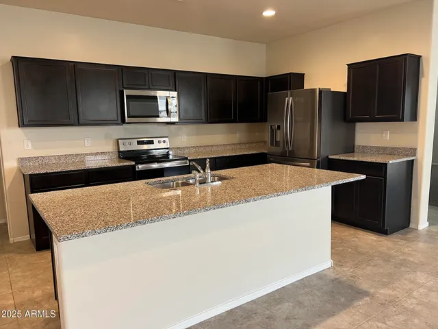 a kitchen with stainless steel appliances granite countertop a sink and a refrigerator