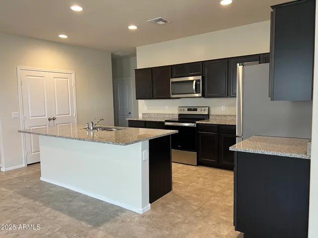 a kitchen with kitchen island stainless steel appliances a sink stove and refrigerator