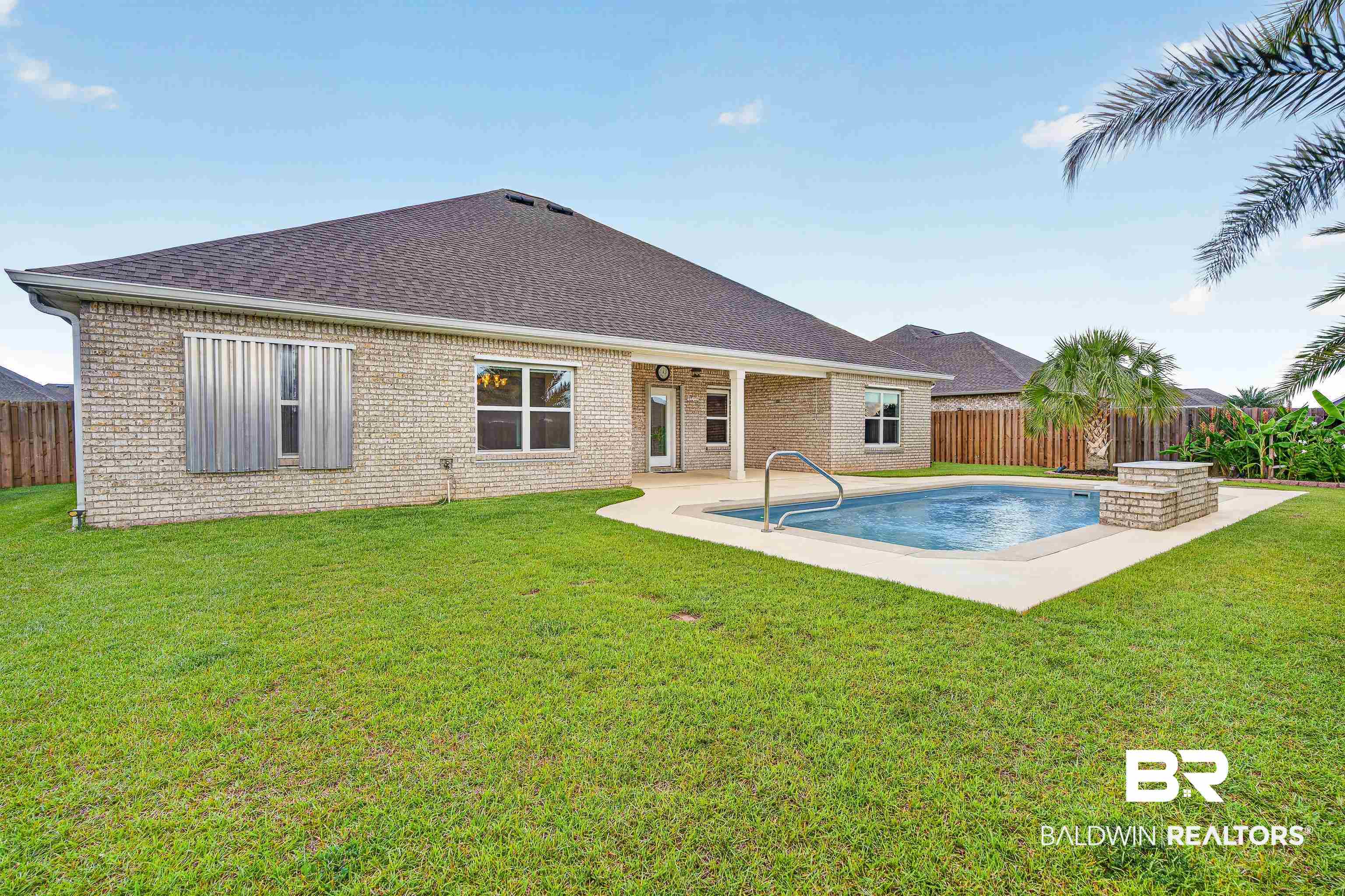 1724 Partridge Street Foley, AL 36535 - Photo 53 of 62 Private backyard featuring an in-ground swimming pool with an integrated sun shelf, a spacious concrete pool deck, and a covered patio