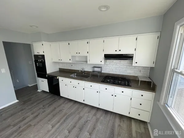 a kitchen with granite countertop a sink a stove a refrigerator and cabinets