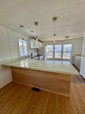 a view of a kitchen with kitchen island a sink wooden floor and a counter top space
