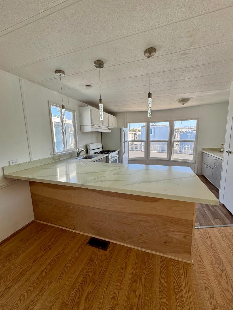 12350 Christensen Road, Unit 76 Salinas, CA 93907 - Photo 2 of 19 a view of a kitchen with kitchen island a sink wooden floor and a counter top space