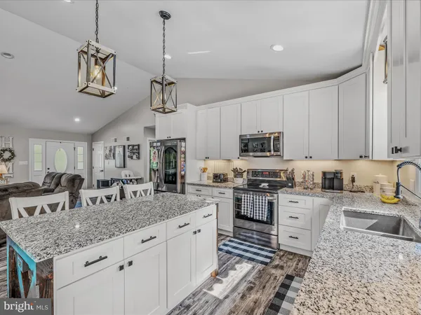 a kitchen with granite countertop a sink a counter space appliances and cabinets