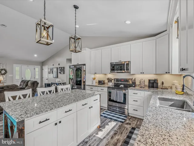 a kitchen with granite countertop a sink a counter space appliances and cabinets