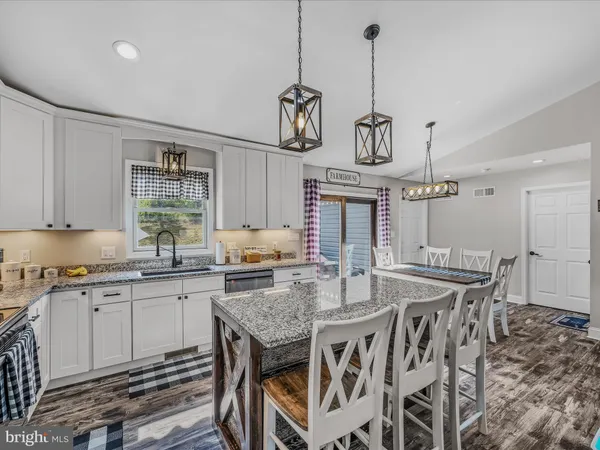 a kitchen with granite countertop a table chairs stainless steel appliances and cabinets