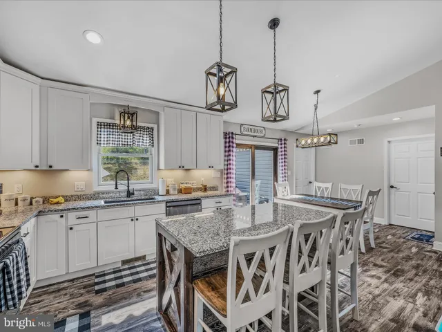 a kitchen with granite countertop a table chairs stainless steel appliances and cabinets