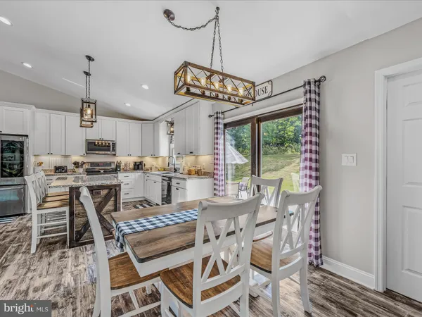 a kitchen with a dining table chairs and large windows