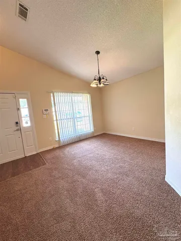 an empty room with a chandelier fan and windows
