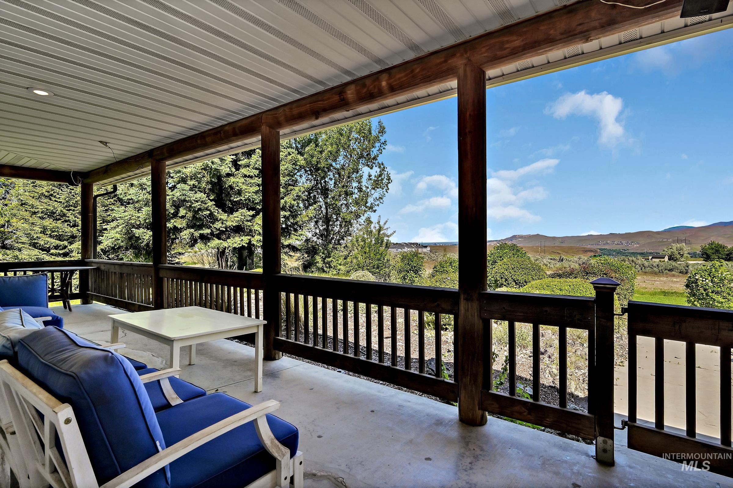 7213 East Columbia Road Boise, ID 83716 - Photo 30 of 47 Covered porch featuring a corrugated metal ceiling, exposed wood beams, and a dark wood railing