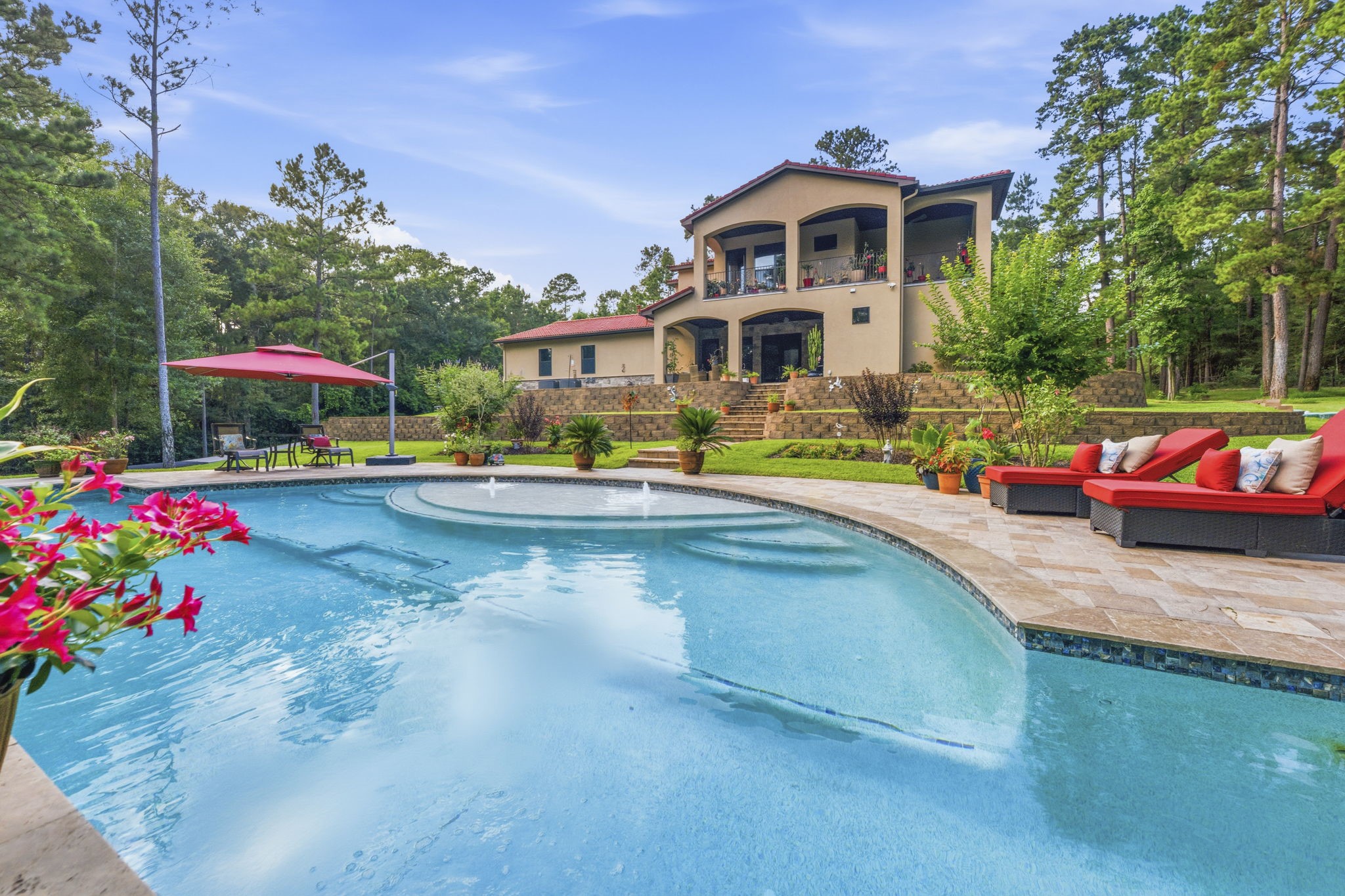 280 Sundog Road Huntsville, TX 77340 - Photo 43 of 50 Poolside view of the rear of the home highlighting inviting areas for lounging and gathering, complemented by waterfalls flowing into the pool.