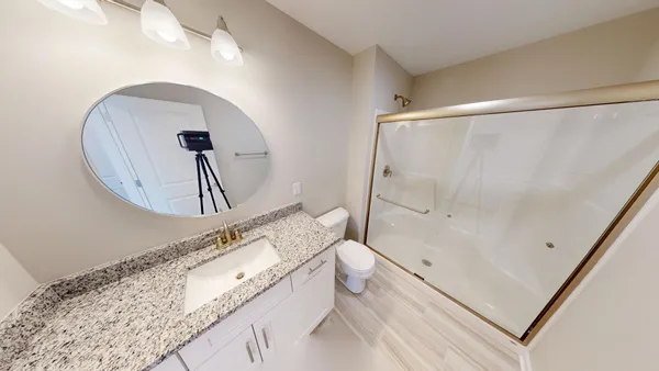 a bathroom with a granite countertop sink mirror vanity and toilet