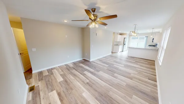 a view of empty room with wooden floor and ceiling fan